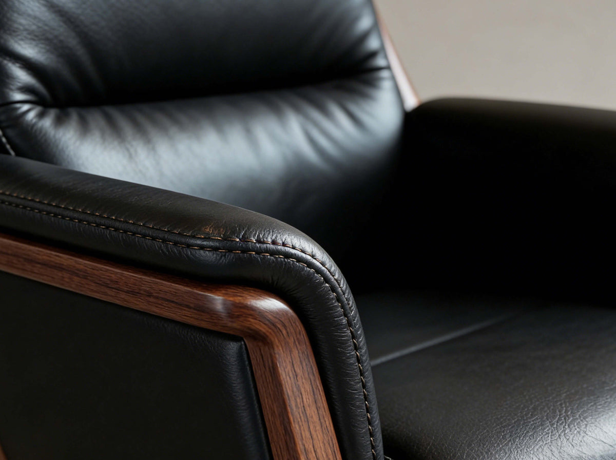 Close-up of a black leather armchair with wooden armrests.
